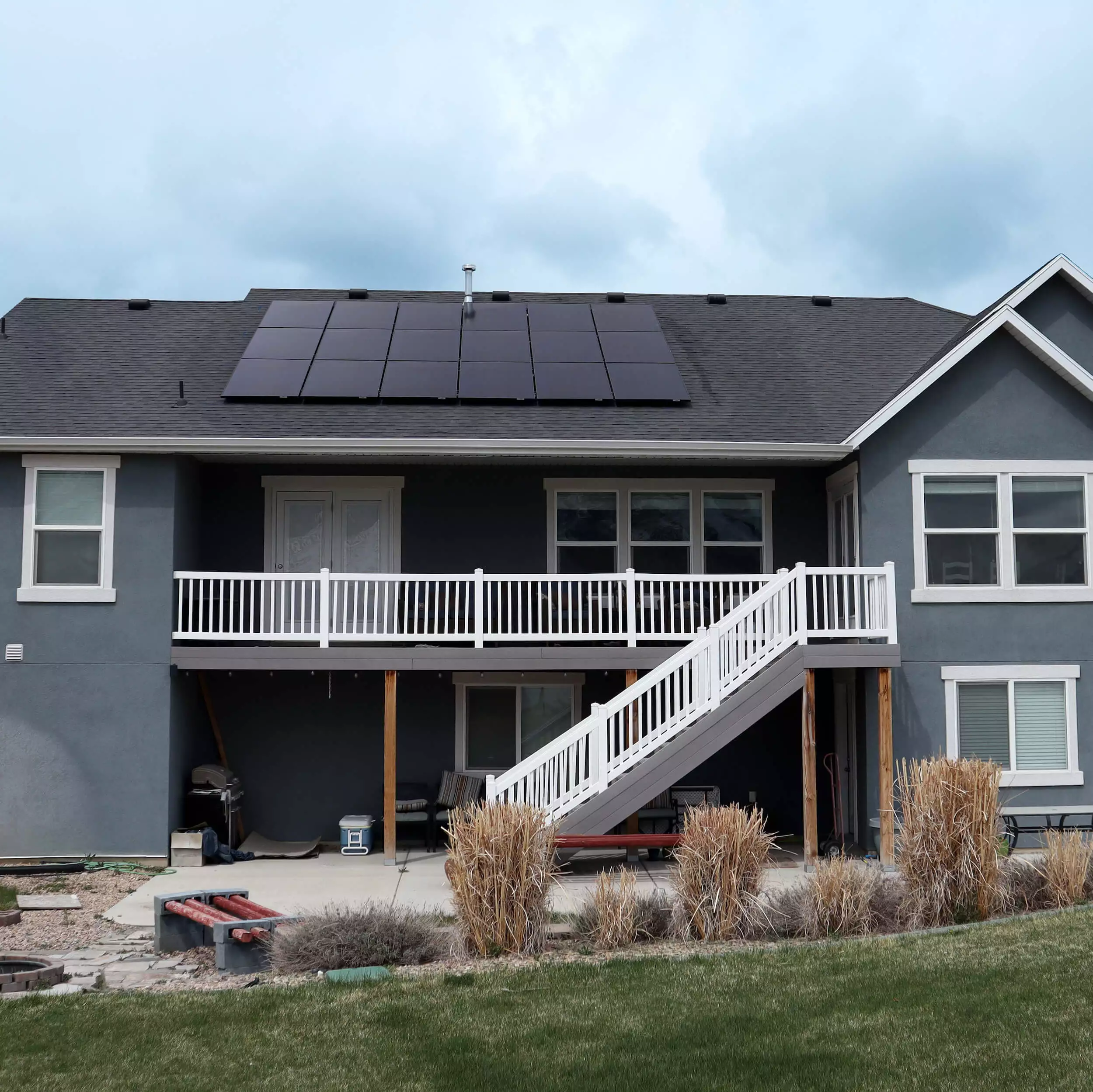 Back preview of two-story, grey-blue house with large solar panel system installed on roof
