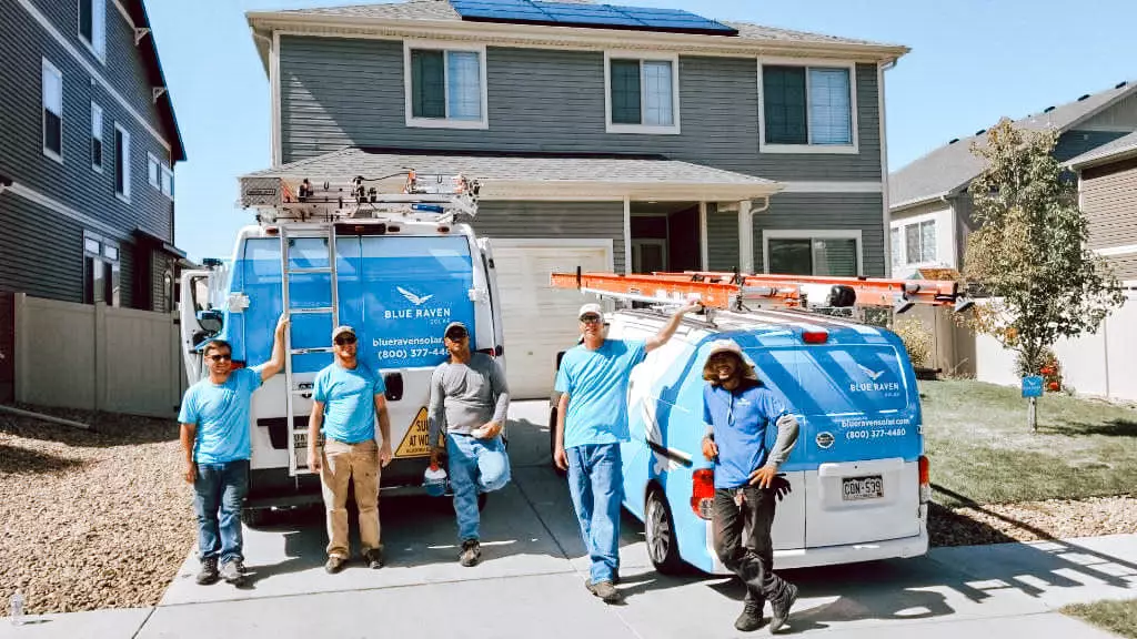 Blue Raven Solar installation crew standing in front of a house with two branded vans