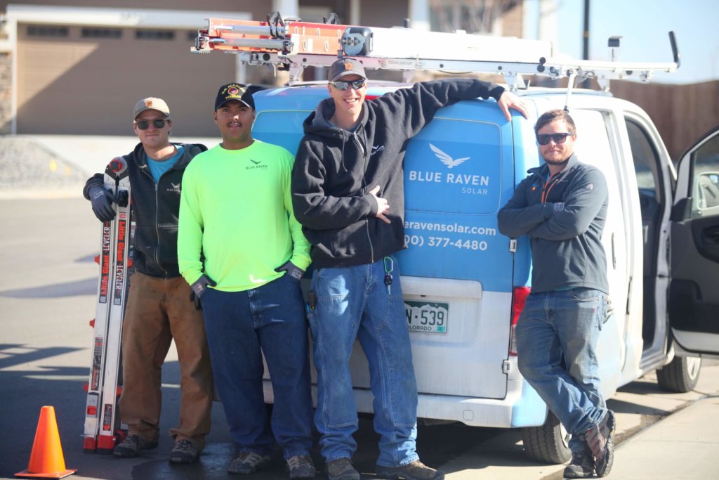 Group of four male Blue Raven Solar installers standing in front of a branded Blue Raven Solar van