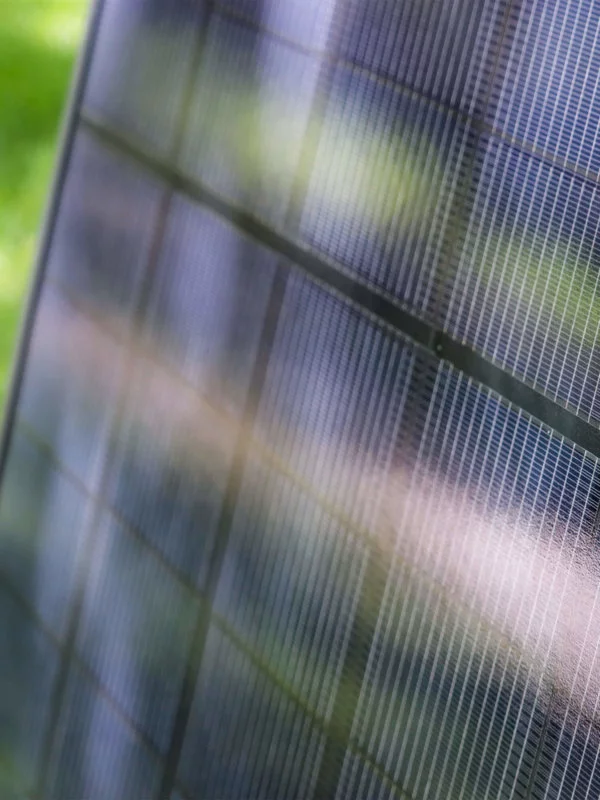 Upclose view of a solar panel used at a Blue Raven Solar installation with green leaves in the background