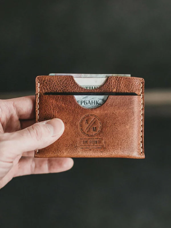 Male holding a brown leather wallet with cash and ID