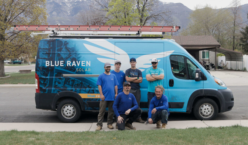 Group of five installation crew members standing in front of a branded Blue Raven Solar van
