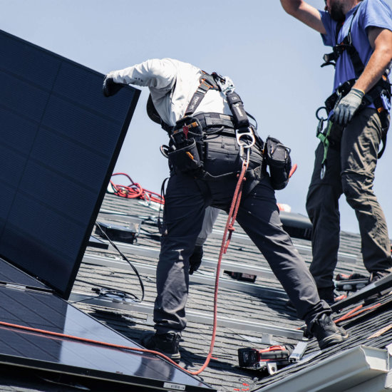 Two Blue Raven Solar installers laying out panels and connecting them to the racking system