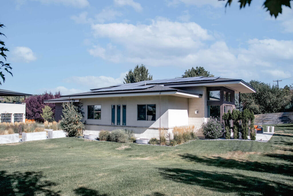 Neutral toned, modern house with relatively low pitch and large solar panel system installed on roof