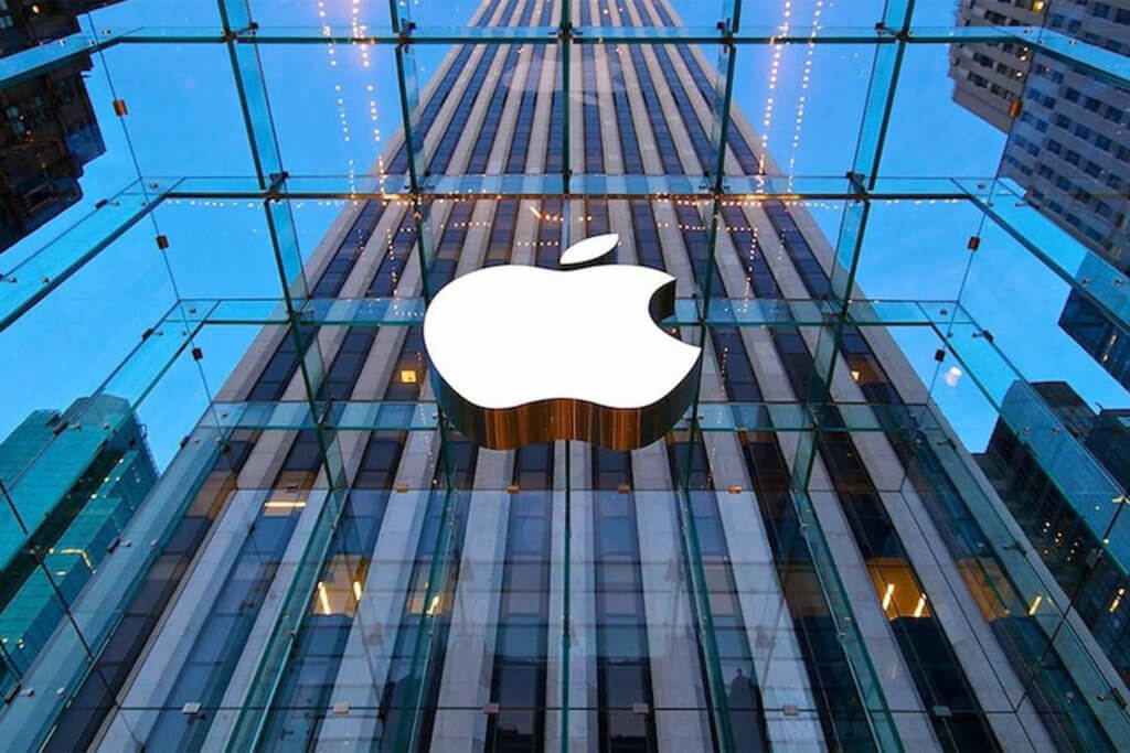 Apple sign installed on a glass building with a larger building behind