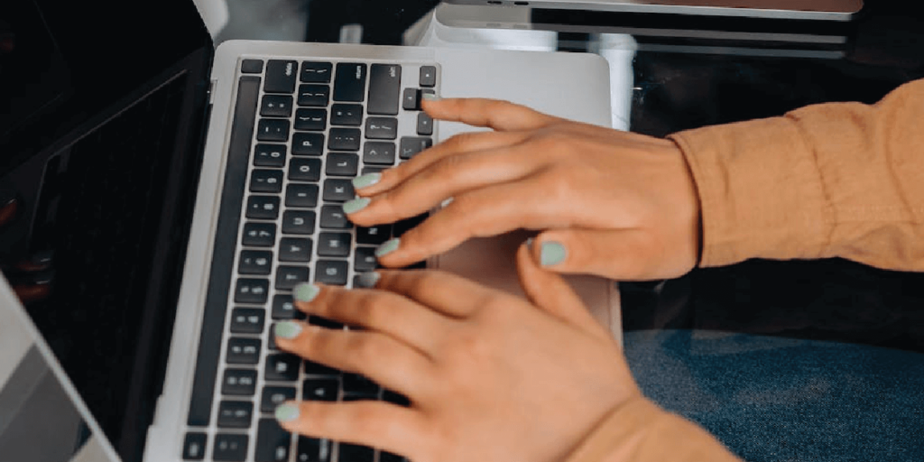 A set of hands typing on a laptop