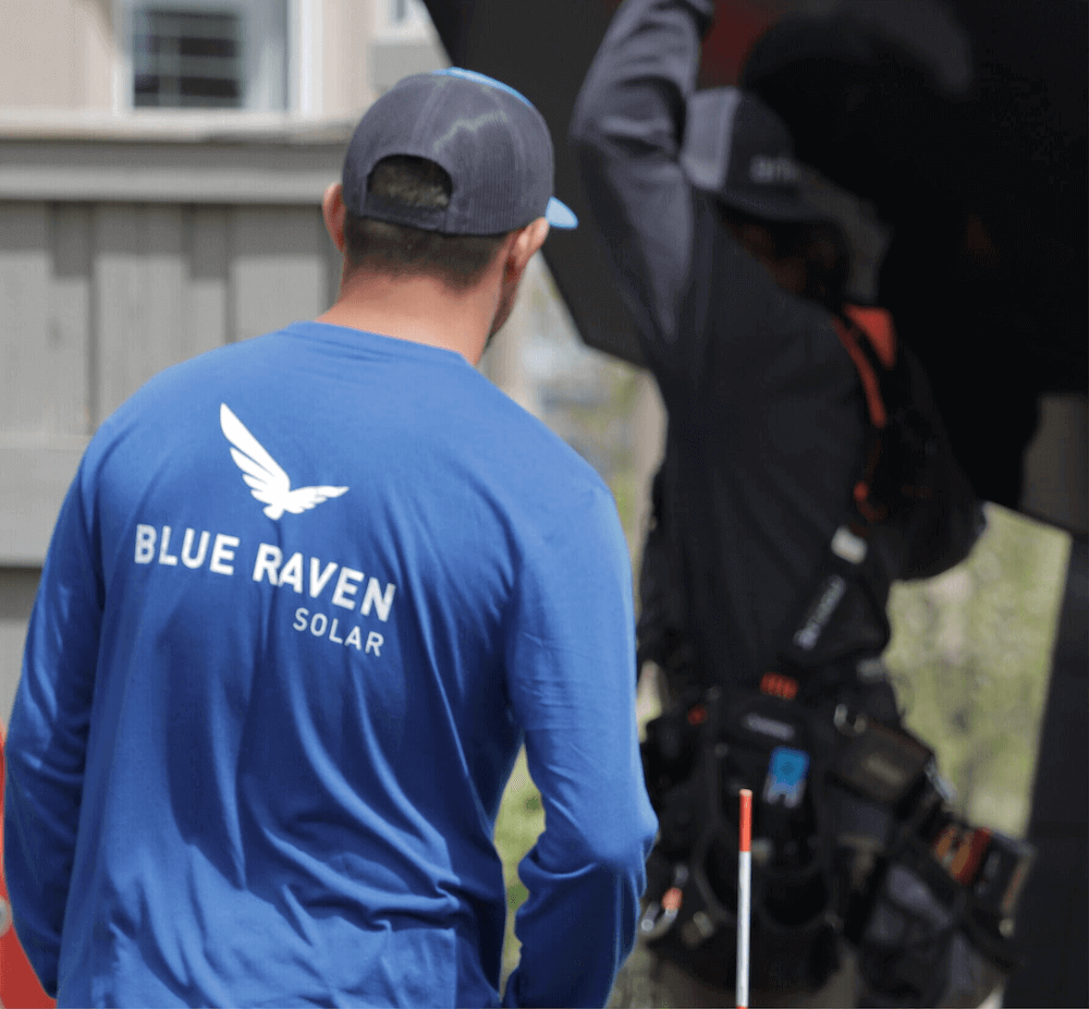Blue Raven Solar installer in a blue branded, long-sleeve t-shirt approaching another install crew member