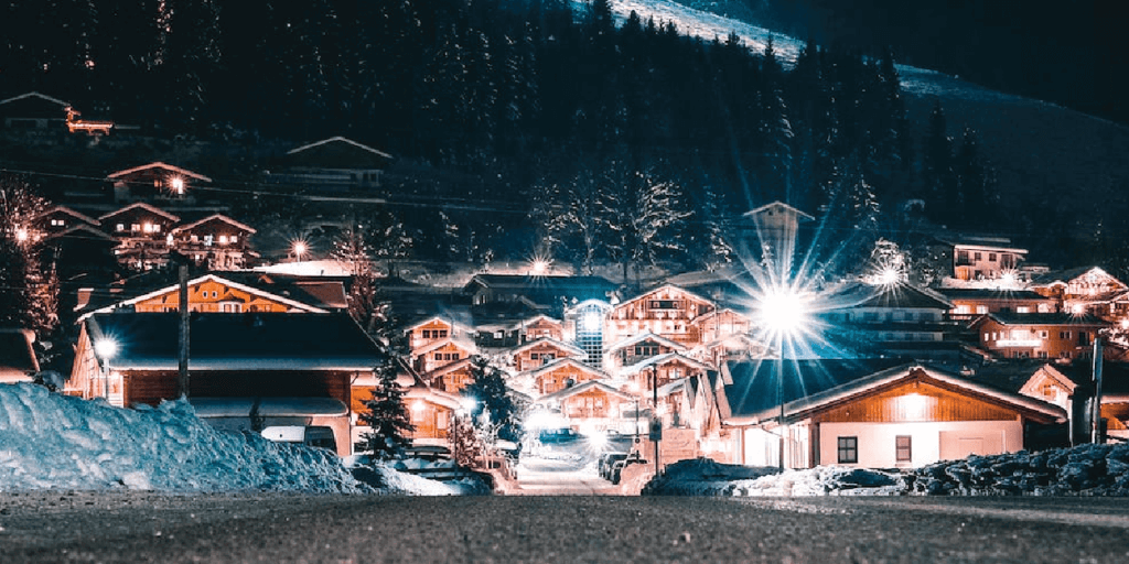 Community of houses at the base of a mountain at night with lights shining bright