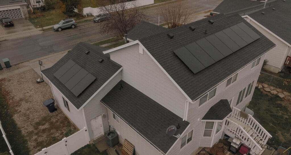 Aerial shot of a large two-story house with solar panels installed on different pitches