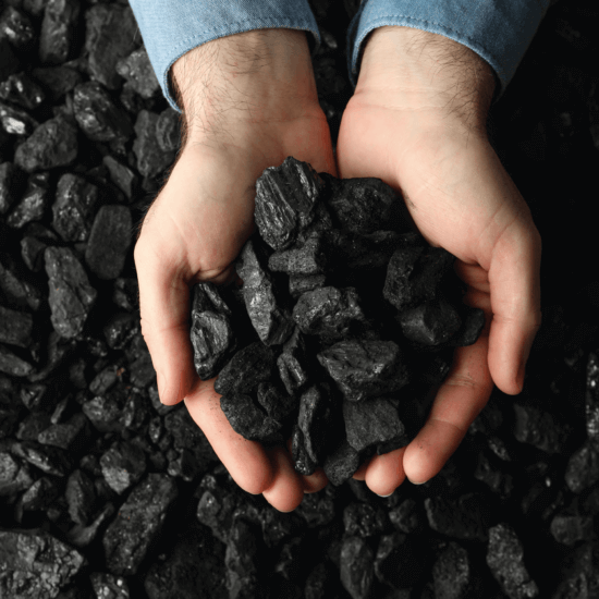 Small pieces of coal, some being held by two hands