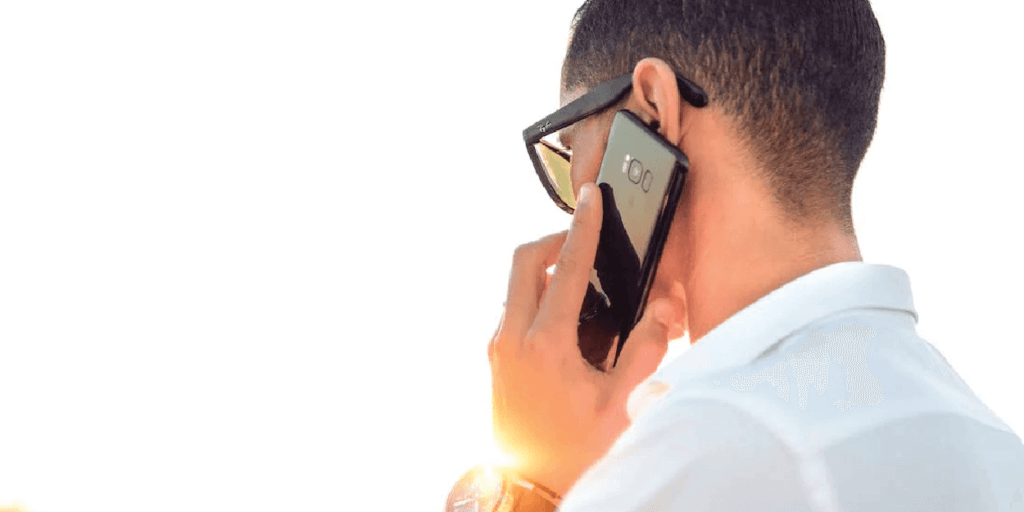 Male in a white, collared shirt talking on a smart phone