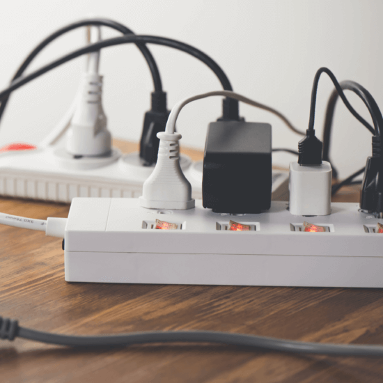 Multiple power strips with numerous products plugged-in sitting on a wood table