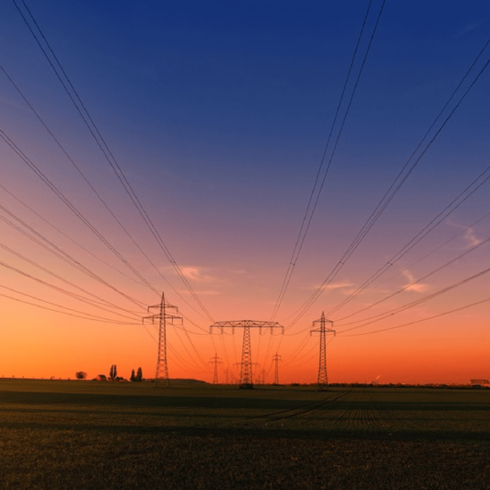 Utility lines with a vibrant sunset in the background ranging from dark blue to yellow