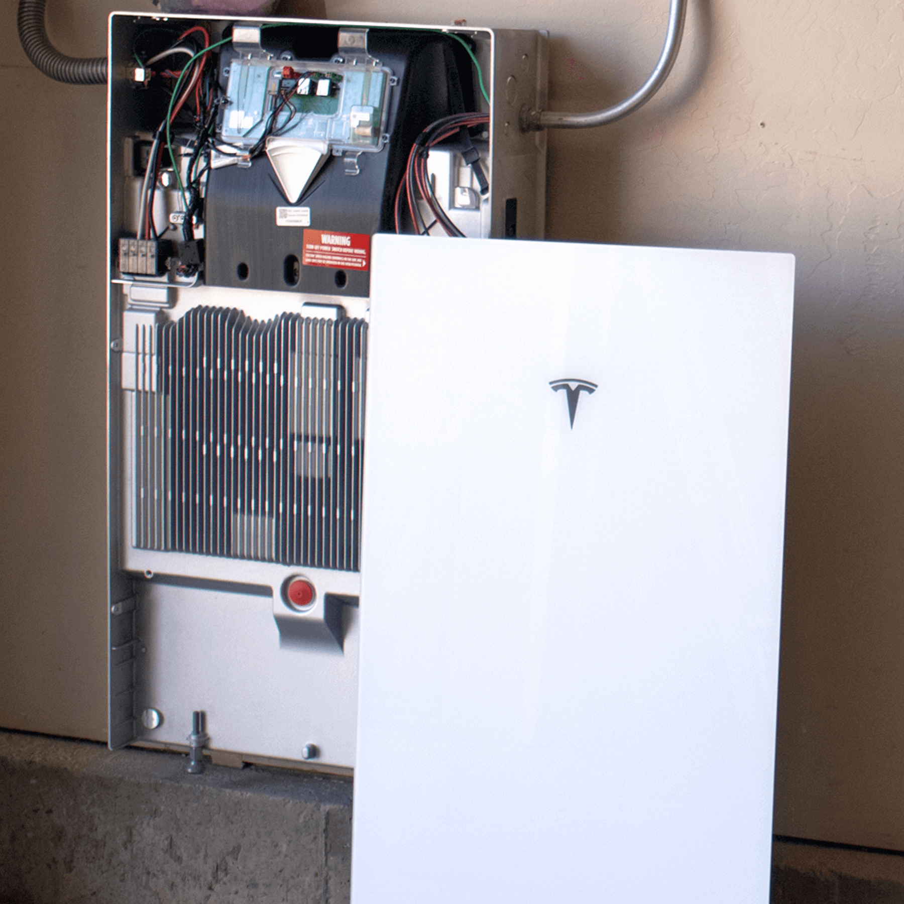 Tesla Powerwall 3 cover and inside of a batter getting installed in a garage