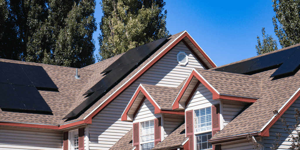 What is a Solar Power Production Guarantee-01 House with brown asphalt shingles, large solar panel installation on multiple pitches