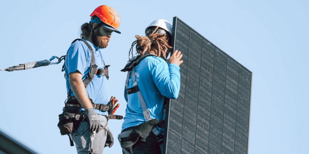 What is a Solar Power Production Guarantee-02 Two Blue Raven Solar installers placing a monocrystalline solar panel on a rooftop