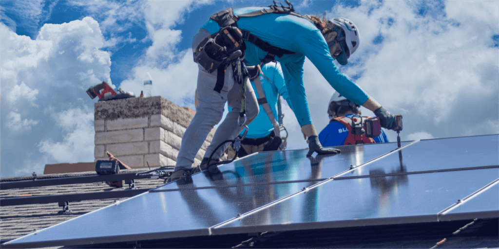 Blue Raven Solar installers securing a monocrystalline solar panel to a roof using specialized tools and racking