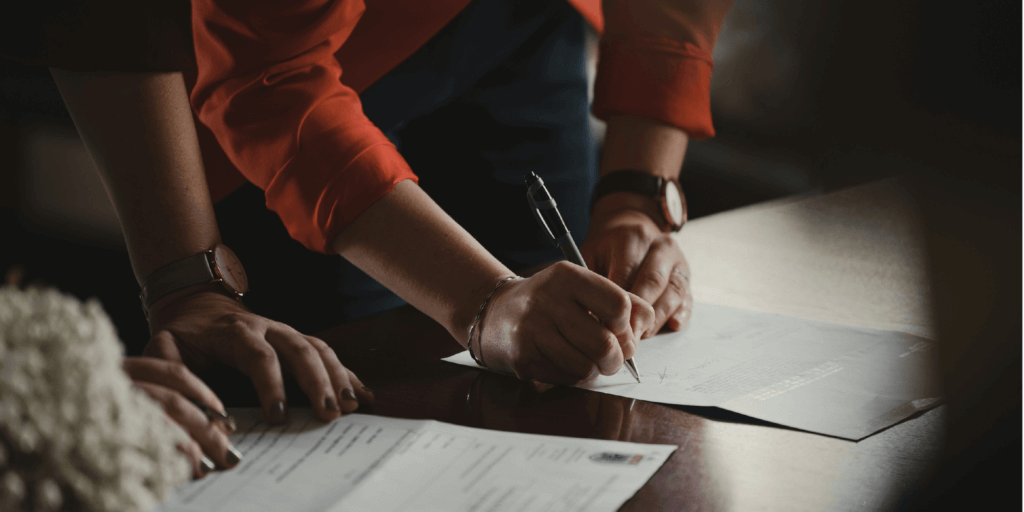 Two individuals signing documentation with a pen