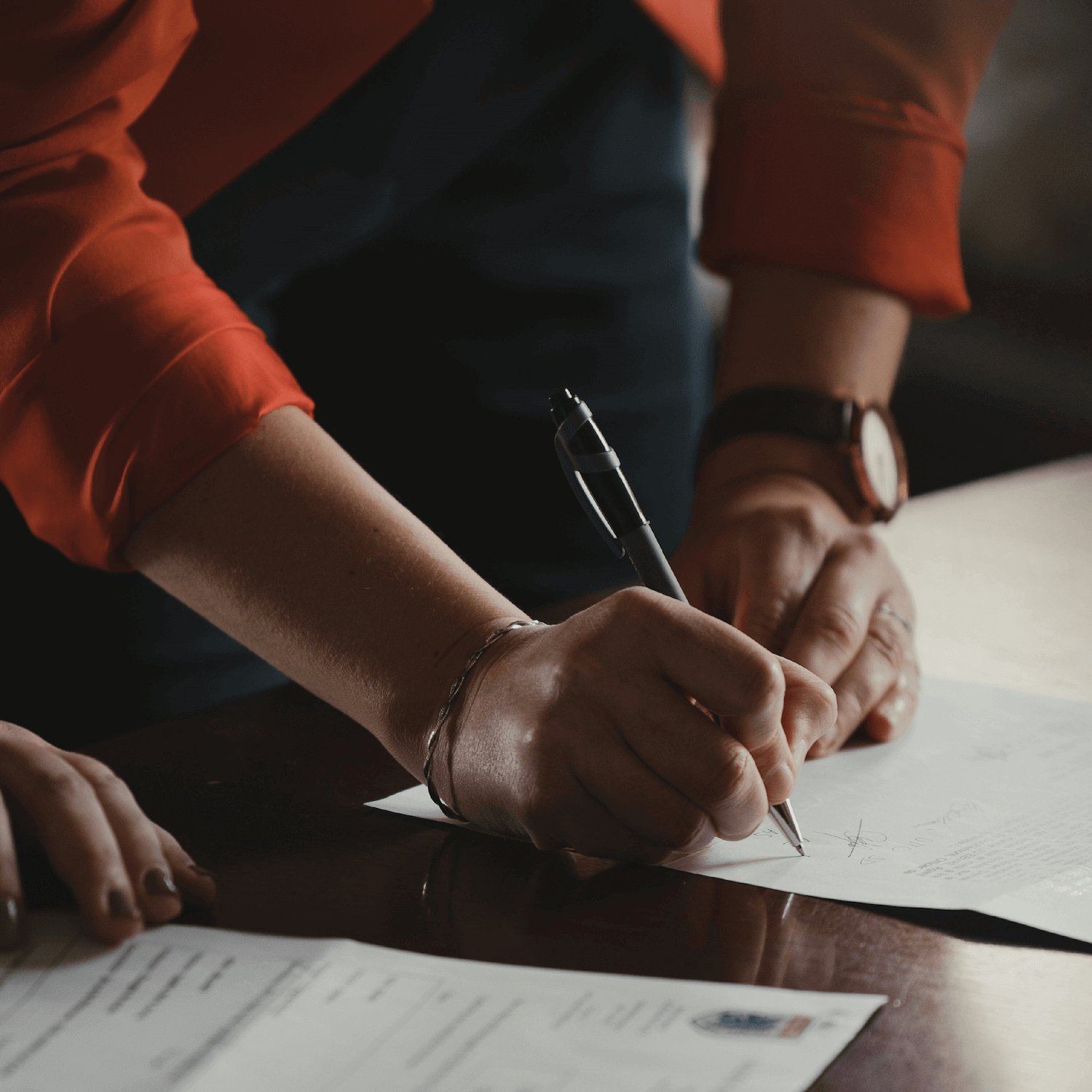 Two individuals signing documentation with a pen